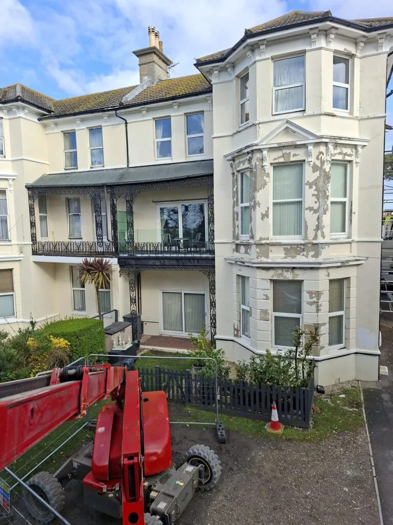 Block of flats in Boscombe before exterior painting showing peeling masonry paint and access equipment in place