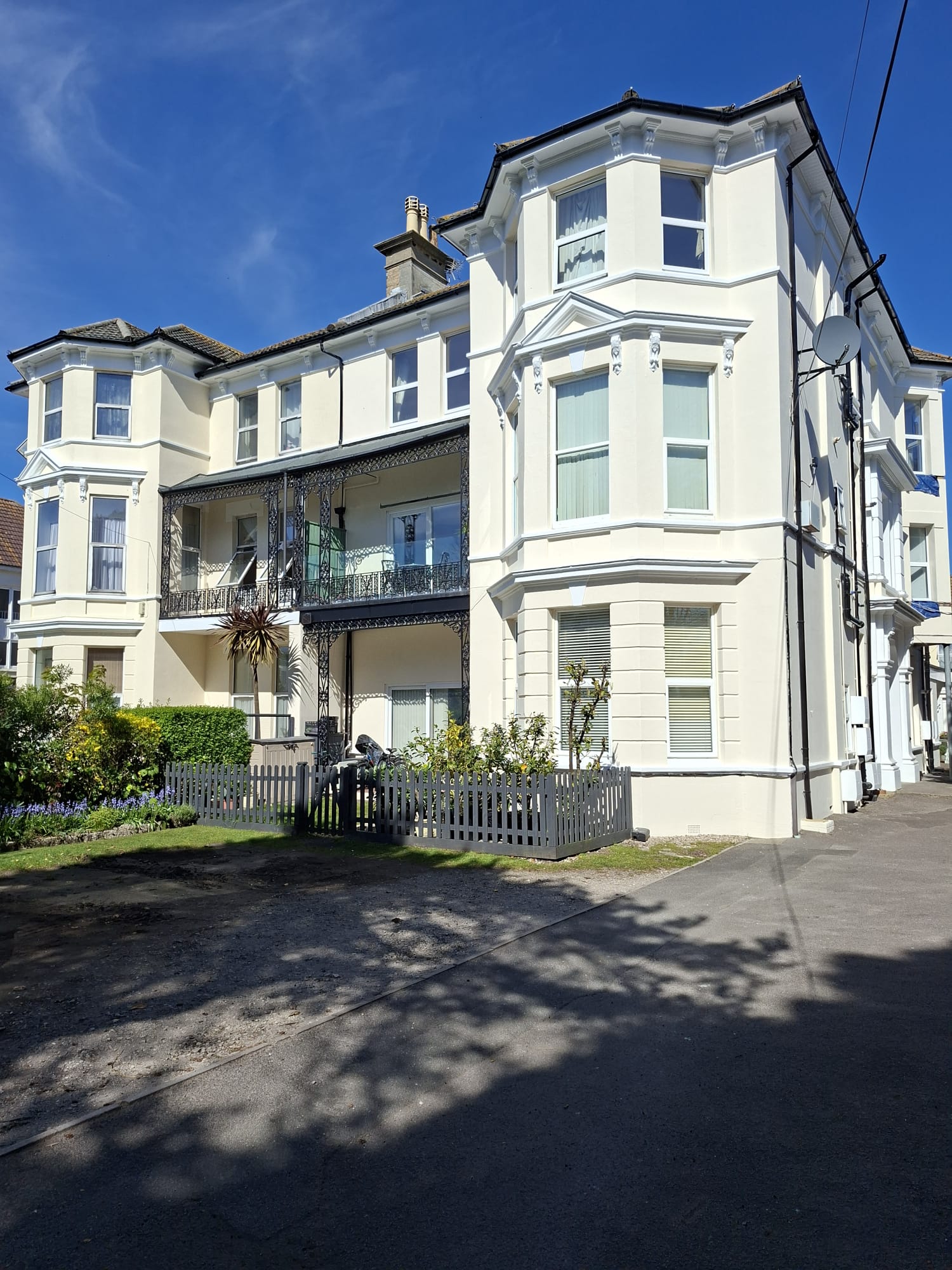 Close-up of completed masonry painting and exterior decorating works on a block of flats in Boscombe showing repaired walls, painted bay windows, soffits, and balcony metalwork.